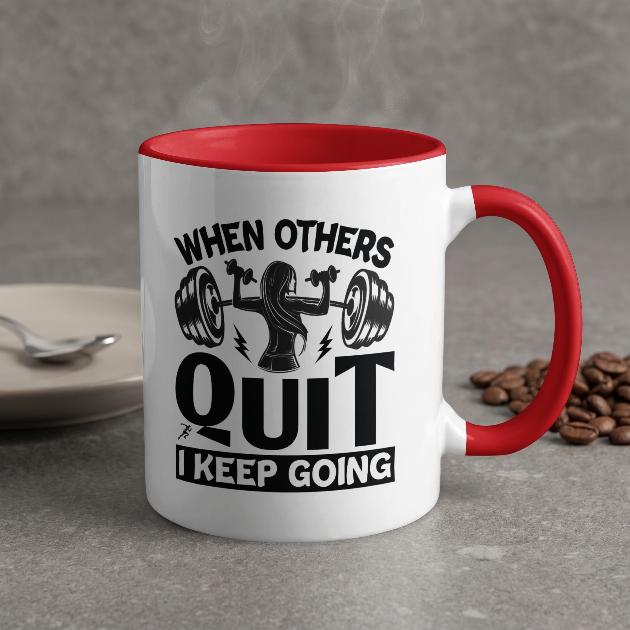 White mug with red handle, "When Others Quit I Keep Going" text, and barbell graphic.