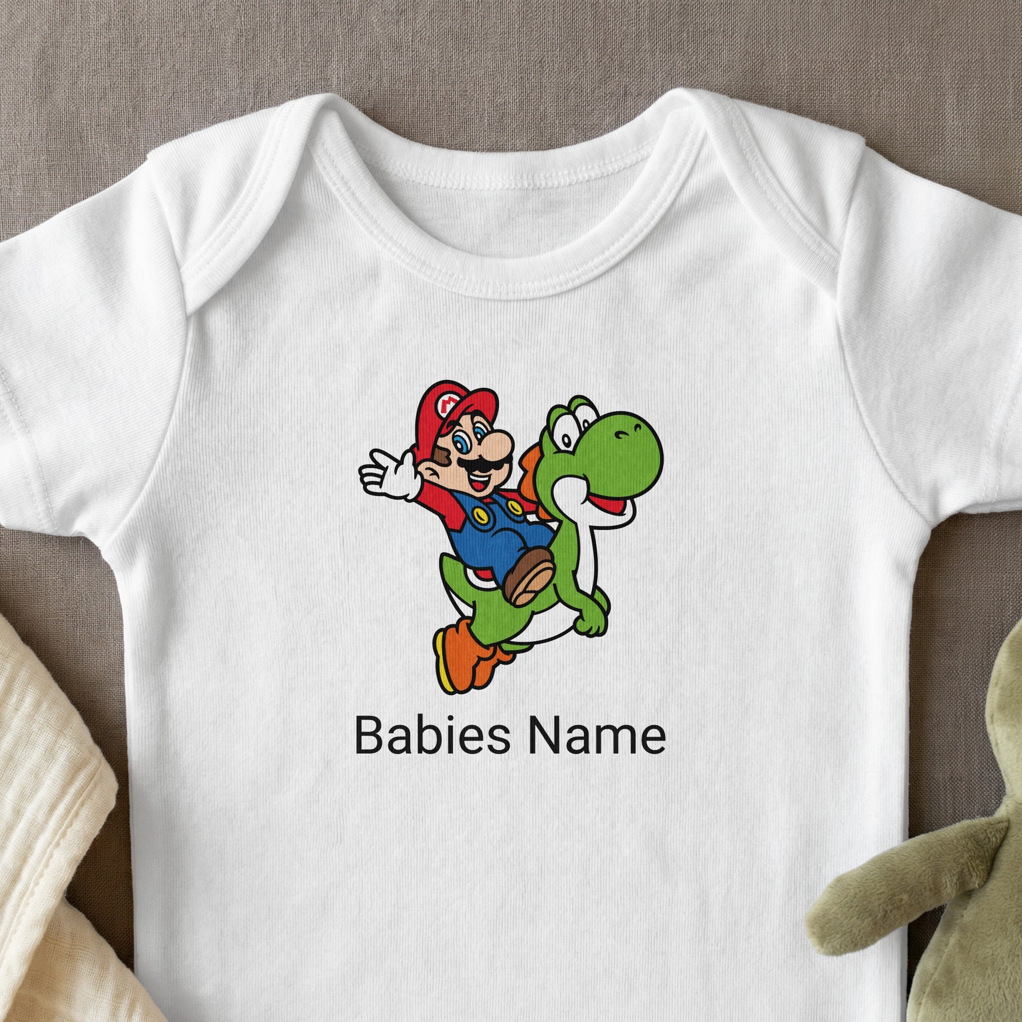 Mario riding Yoshi on a white baby onesie with text "Babies Name".
