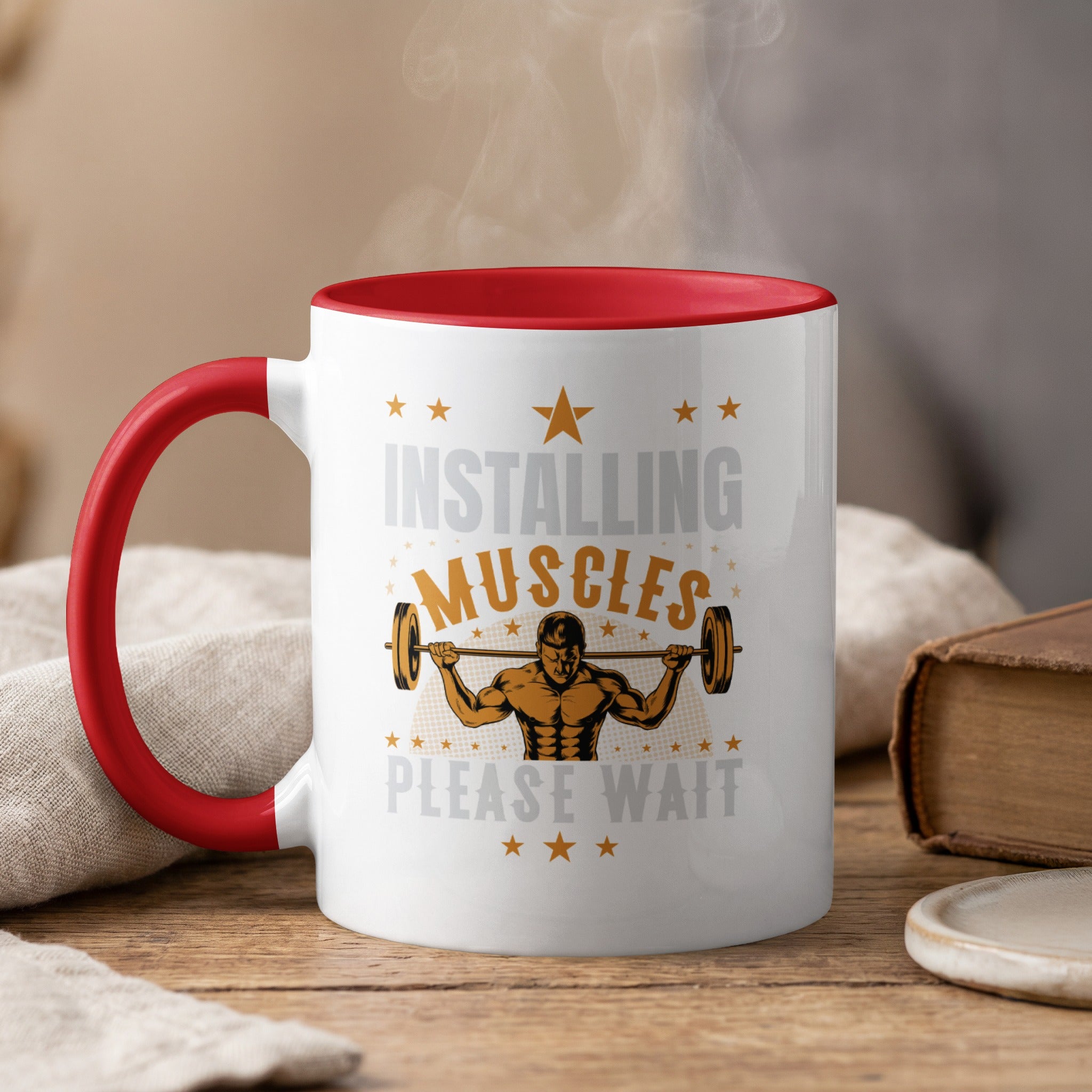 White mug with red handle, "Installing Muscles Please Wait" text, and barbell graphic.
