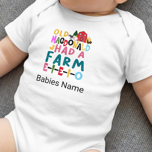 White baby onesie with "Old MacDonald Shad A Farm E-I-E-I-O" text and farm graphics.