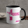 White mug with black rim, "DOING ME" in pink text and silhouette.