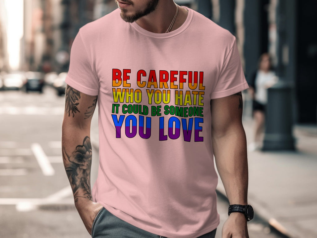 Pink t-shirt featuring rainbow text: "BE CAREFUL WHO YOU HATE IT COULD BE SOMEONE YOU LOVE".