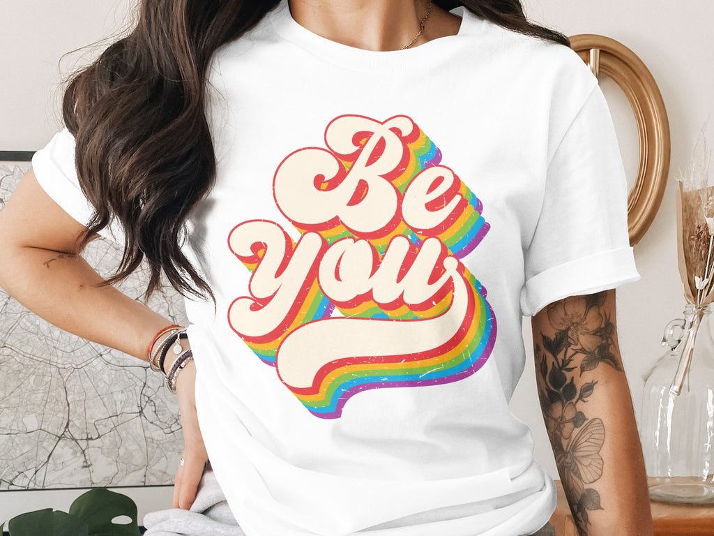 White t-shirt with "Be You" in retro rainbow lettering.