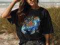 Black t-shirt featuring a blue walrus adorned with colorful flowers and floral patterns.