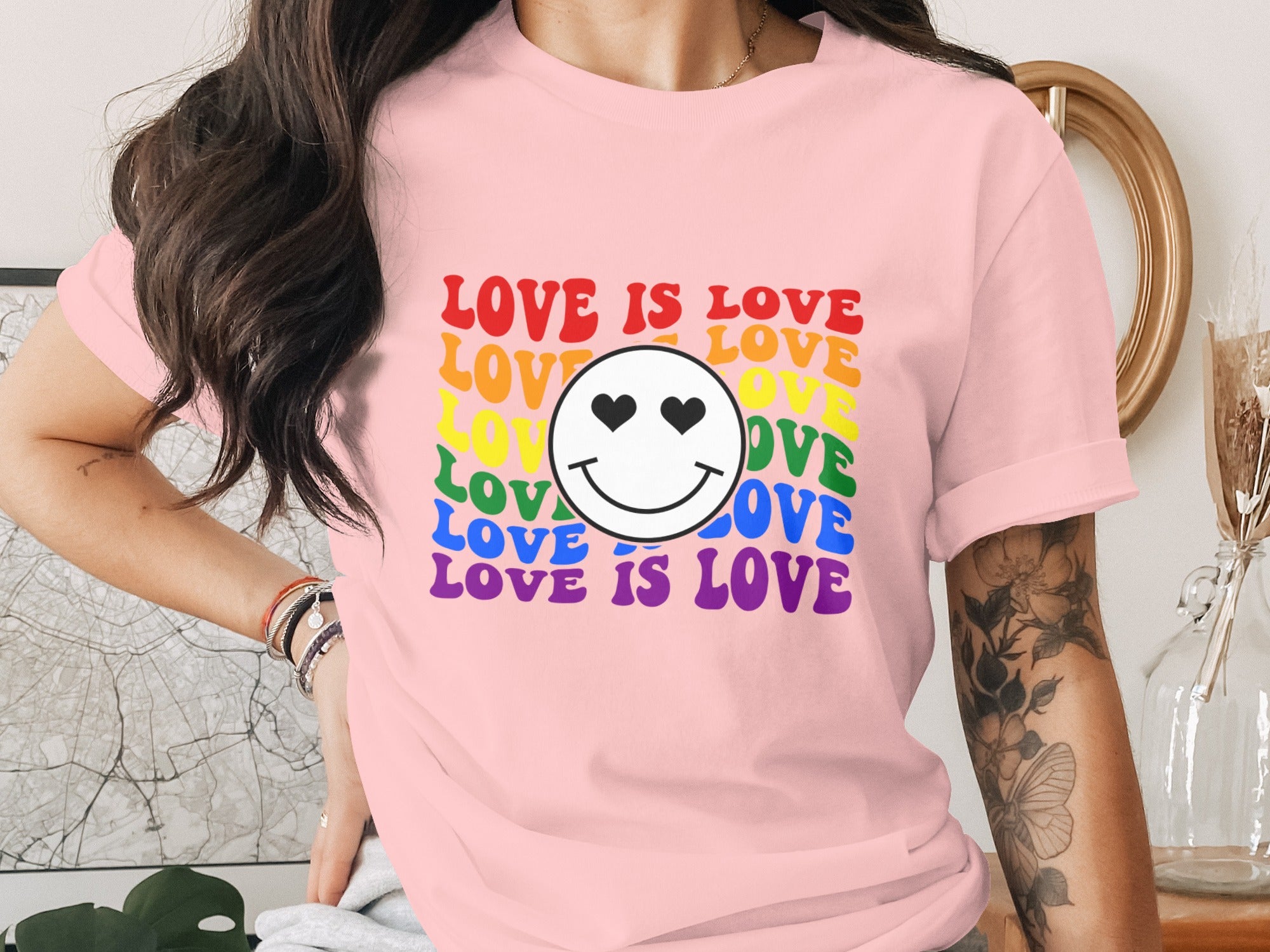 Pink t-shirt with "LOVE IS LOVE" and smiley face with heart eyes in rainbow colors.
