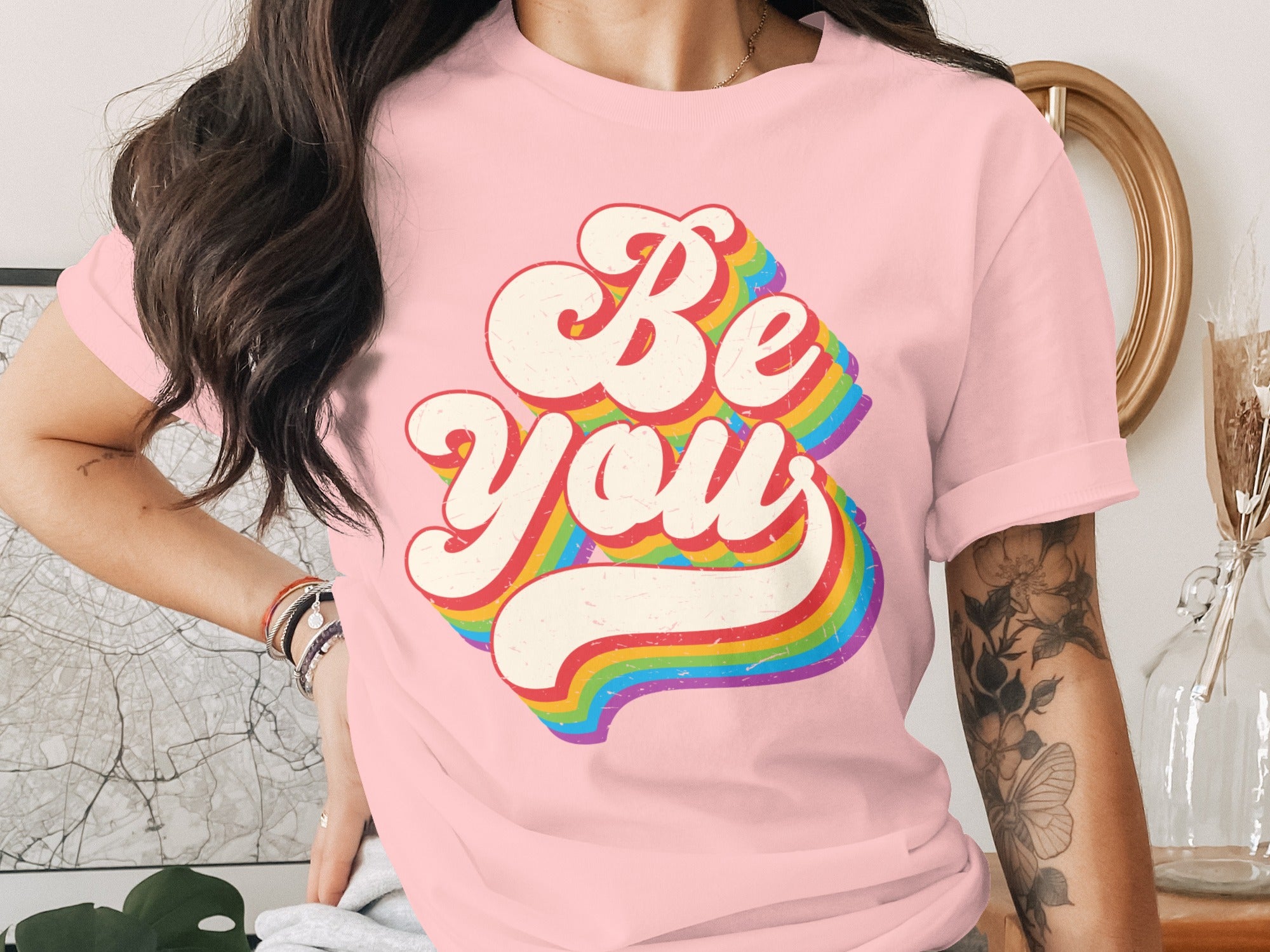 Pink t-shirt with retro "Be You" text in rainbow colors.