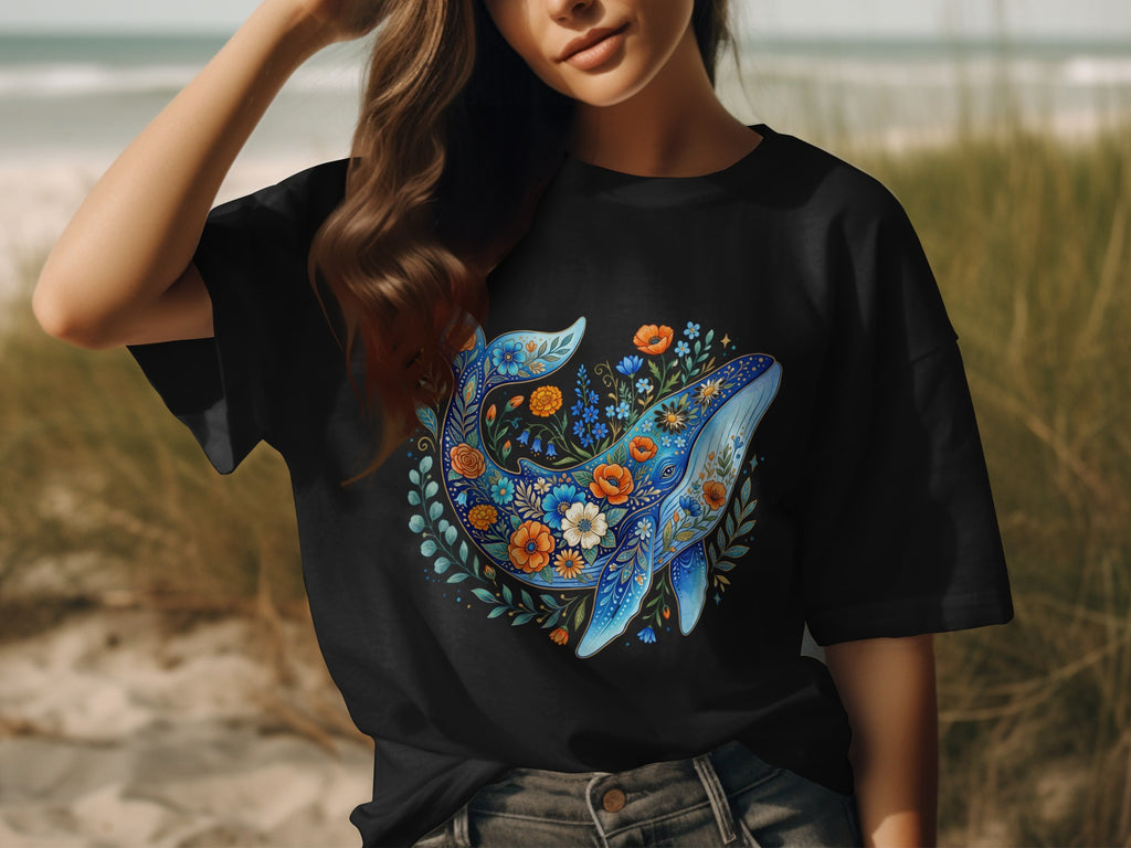 Black t-shirt with a blue whale design surrounded by colorful flowers.