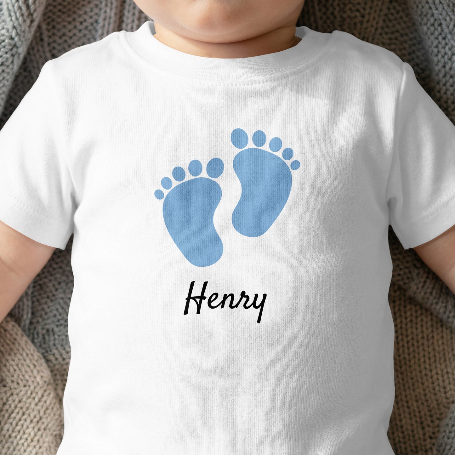 White baby t-shirt with blue footprints and "Henry" text.