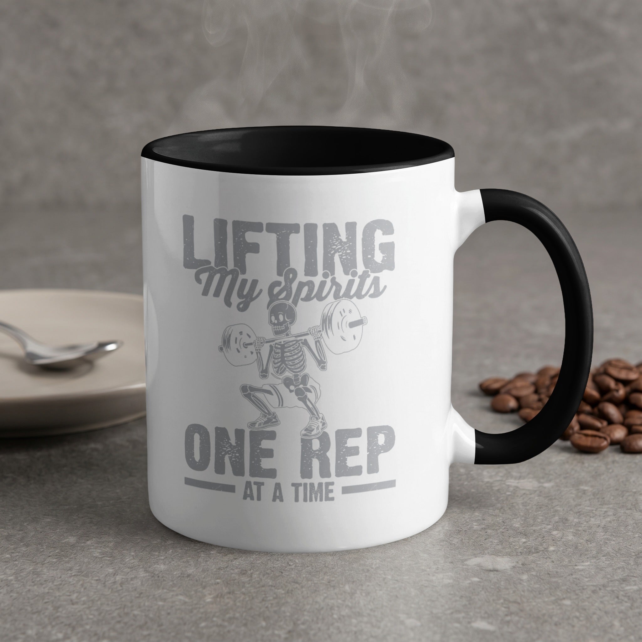 White mug with black rim, skeleton lifting weights, "Lifting My Spirits ONE REP AT A TIME".